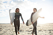 Happy female surfers running with surfboards on sunny beach