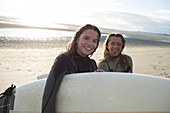 Happy young female surfers with surfboard on sunny beach