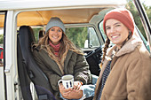 Happy young women friends drinking coffee in van doorway