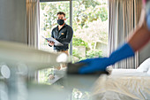 Hotel manager in facemask inspecting hotel worker cleaning
