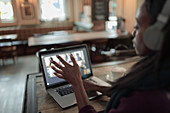 Businesswoman with headphones video conferencing at laptop