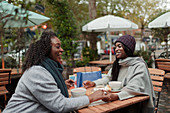 Mother and daughter holding hands and eating lunch on patio