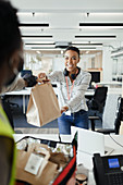 Happy businesswoman receiving lunch delivery from courier