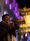 Happy woman with camera at Chinatown Gate, London, UK