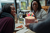 Waitress serving birthday cake to mother and daughter