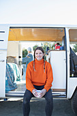 Confident young woman drinking coffee at camper van doorway