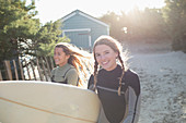 Happy young female surfer with surfboard on sunny beach path