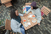 Mother and daughter holding hands and eating lunch at cafe