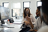 Businesspeople in facemasks video conferencing at computer