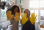 Mother and daughter gesturing in yellow rubber gloves