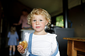 Girl with curly blonde hair eating biscuit at home