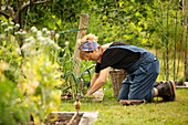 Woman tending to plants in summer vegetable garden