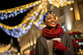 Happy woman with Christmas light headband in city at night