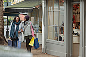 Mother and daughter walking arm in arm with shopping bags