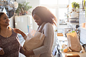 Mother and daughter unloading groceries in kitchen