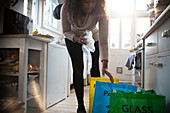 Woman sorting recycling into bags on kitchen floor