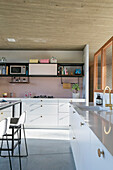 White fitted kitchen units and pink wall tiles