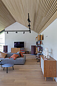 Seating area with low sideboard and shelves in high-ceilinged, open-plan interior