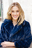 A young blonde woman wearing a blue faux fur coat