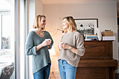 Friends drinking coffee in front of piano in living room