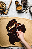 Schokoladenschnecken zubereiten: Flüssige Schokolade auf Teig streichen