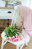 Pink tulips and wooden bunny on a white chair