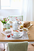 Breakfast table set with muesli, tea, loaf of bread and tulips