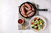 Grilled Salsiccia (italian sausages) in pan with tomato sauce and vegetable salad