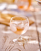 A glass of rose wine with ice cubes on a wooden table