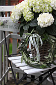 Weiße Hortensie im Korb mit Kranz aus Olivenblättern