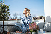 Blonde Frau in Freizeitbekleidung sitzt auf der Terrasse