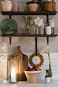 Candle burns under the wintry decorated shelf in a country house kitchen