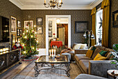 Beleuchteter Weihnachtsbaum im Wohnzimmer mit Vintage Couchtisch, Sofa und Tapete