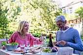 Älteres Paar beim Essen am gedecktem Tisch im Freien