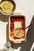Baked feta cheese with tomatoes and pasta on a baking dish