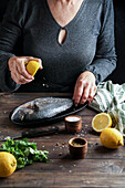 Woman chef preparing a fresh fish dorado by cutting