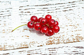 Red currants on a white wooden background