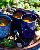Antique enamel mugs with tomato soup topped with basil and whole wheat croutons
