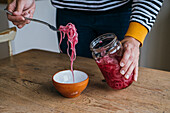 Person putting pickled red onion into bowl