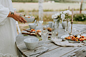 Frauenhände legen Essen auf den Tisch im Garten