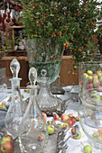 Autumn arrangement with glass carafes, apples and bouquet of rose branches with rose hips