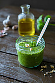Basil pesto in a jar on a wooden table