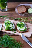 Two pieces of muesli bread with cream cheese, cucumber, and dill