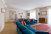 Blue upholstered sofas and antique chest of drawers with dining area in the background