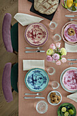 Gedeckter Tisch mit bemalten Tellern und Blumenstrauß