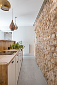 Narrow kitchen with natural stone wall in an open room