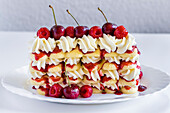 Raspberry tiramisu, layers of sponge, cream and fruit sauce, decorated with fresh raspberries and cherries