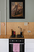 Küchenzeile mit Gasherd, darüber Holzpaneel und Vintage Gemälde