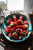 Strawberries in a blue bowl in a rustic kitchen