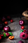 A basket and fresh plums on a rustic kitchen table